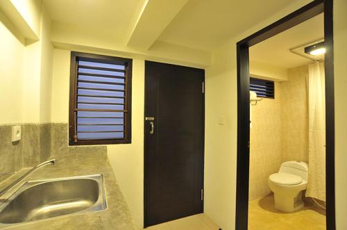 baño con lavabo y aseo y ventana en Ganga Hotel & Apartment, en Denpasar