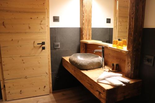a bathroom with a stone sink and a mirror at Hotel Ciasa Lorenzi in Cortina dʼAmpezzo