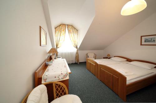 1 dormitorio con 2 camas, mesa y ventana en Penzion Chalupa U Městské brány, en Vyškov