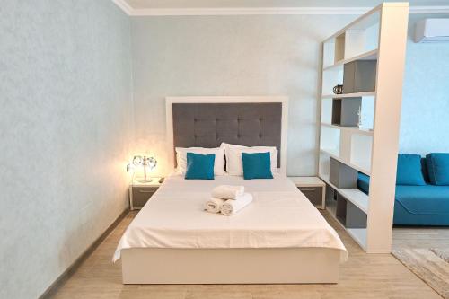een slaapkamer met een bed met blauwe kussens en een blauwe bank bij Moonlight Studio - Spa n Pools beach Resort in Mamaia