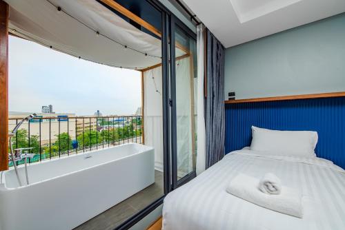 a bedroom with a tub and a bed and a window at Seamira House Huahin in Hua Hin