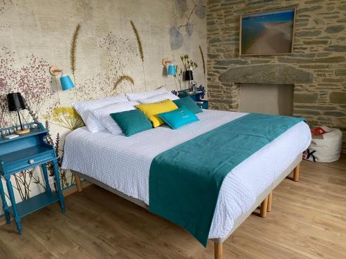 une chambre avec un lit avec des oreillers bleus et jaunes dans l'établissement L’ARDOISIÈRE, maison d’hôtes et d’amis, à Locquirec