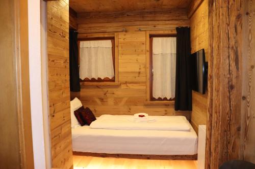 a bedroom with a bed in a wooden room at Hotel Ciasa Lorenzi in Cortina dʼAmpezzo