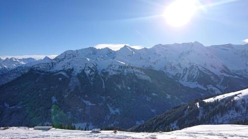 a snow covered mountain range with the sun in the sky at Hoamatl, Appartement in Tux