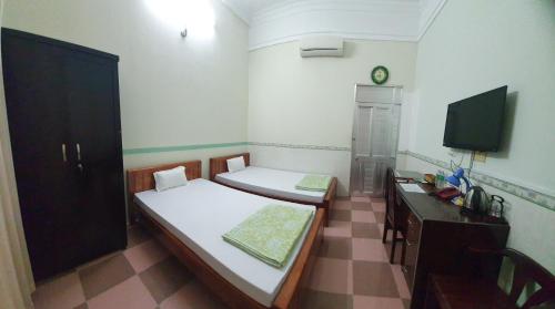 a room with two beds and a television in it at Khách Sạn Ngọc Hân in Tinh Bien