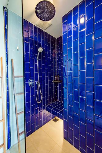 a blue tiled bathroom with a shower with a glass door at Seamira House Huahin in Hua Hin