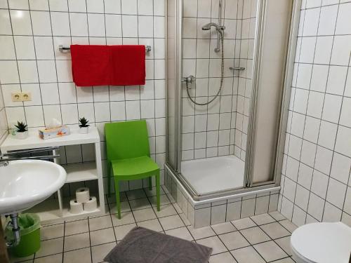 baño con ducha y silla verde en Winzerhof Spengler en Külsheim