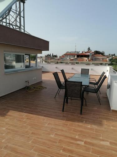 a patio with a table and chairs on a roof at Crystal Blue Apartments in Nea Kalikratia