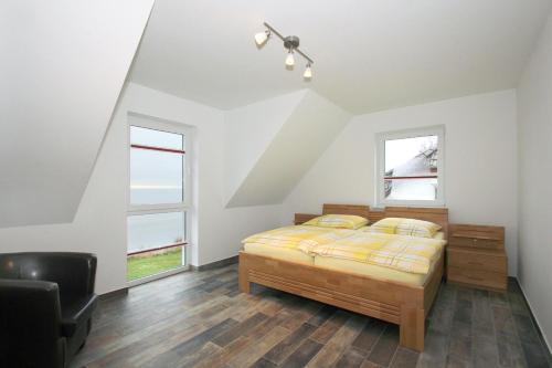 ein Schlafzimmer mit einem Bett und zwei Fenstern in der Unterkunft F-1037 Haus Neuendorf - Kaminfeuer in Putbus