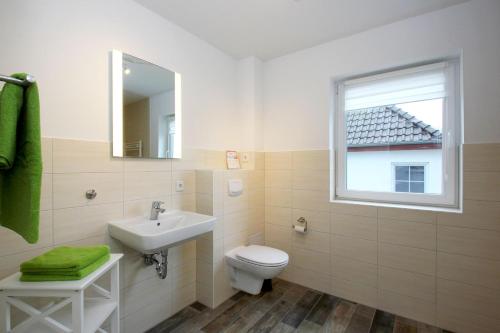 a bathroom with a toilet and a sink and a window at F-1037 Haus Neuendorf - Kaminfeuer in Putbus