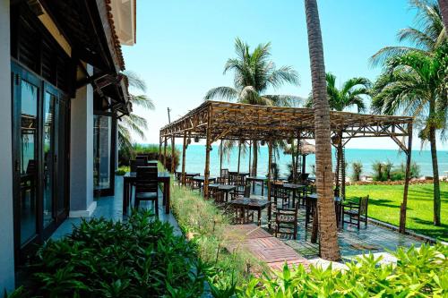 um restaurante com mesas e cadeiras e o oceano em Muine Century Beach Resort & Spa em Mui Ne