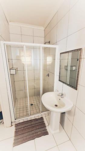 a white bathroom with a shower and a sink at Sheilas Self-Catering Overnight Accommodation in Polokwane
