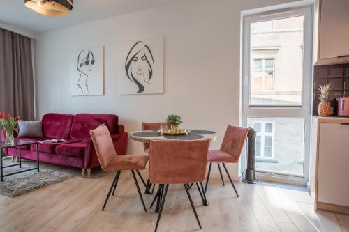 sala de estar con sofá púrpura, mesa y sillas en W&K Apartments White&Grey, en Koszalin