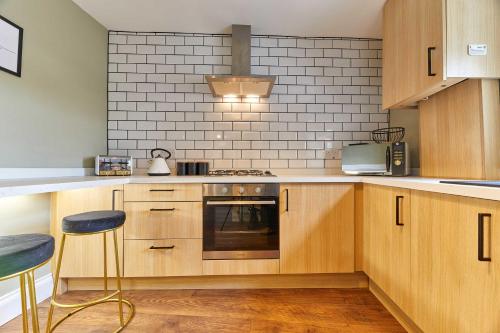a kitchen with wooden cabinets and a stove top oven at Host & Stay - The Blacksmiths in Warkworth