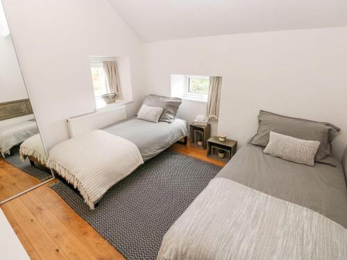 two beds in a room with white walls at Little Bobbins in Saundersfoot