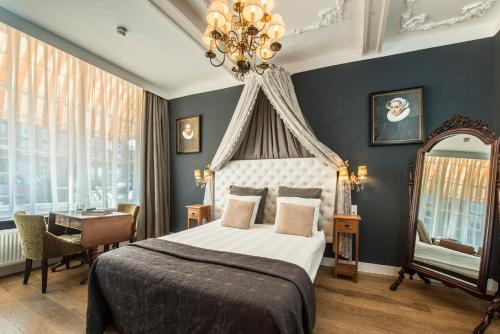 1 dormitorio con cama, escritorio y lámpara de araña en Boutique Hotel Huys van Leyden, en Leiden