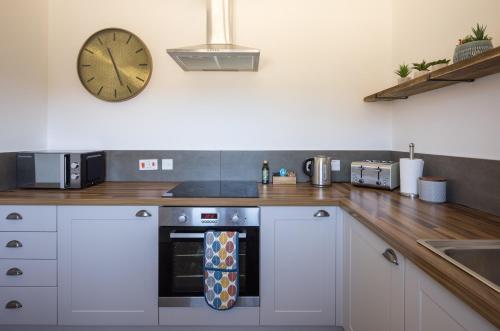 a kitchen with a stove and a clock on the wall at Clopton Courtyard Cambridge in Cambridge