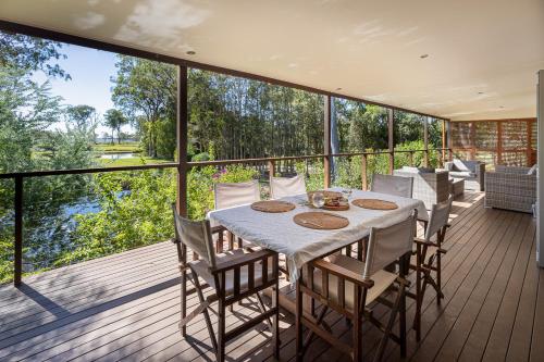 a dining room with a table and chairs on a deck at Lake Weyba Cottages Noosa in Peregian Beach