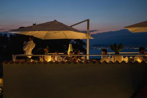 a group of people sitting under an umbrella on a roof at Hotel Vista di Capri in Massa Lubrense