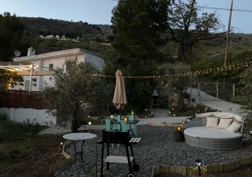 a patio with a table and an umbrella and a couch at Finca Las Fuentezuelas in Carataunas