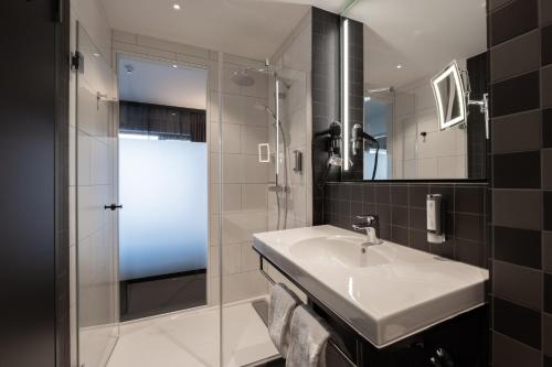 uma casa de banho com um lavatório e um chuveiro em V8 Hotel Köln at MOTORWORLD em Colônia