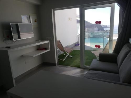 salon z kanapą i przesuwnymi szklanymi drzwiami w obiekcie Puerto Príncipe w mieście Puerto Rico de Gran Canaria