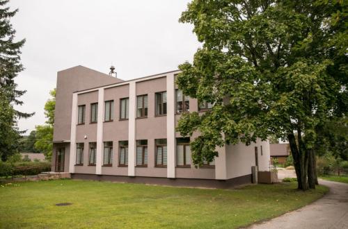 a large white building with a tree in front of it at Žvejo krantas Palūšė in Palūšė