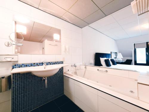 a bathroom with a sink and a bath tub at Hotel De Schout in Denekamp