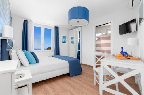 a white and blue bedroom with a bed and a desk at Hotel Vista di Capri in Massa Lubrense