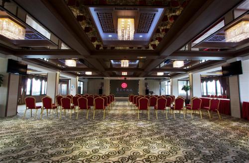 a banquet hall with red chairs and a stage at Hôtel Huatian Chinagora in Alfortville