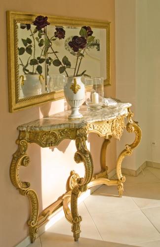a gold console table with a mirror and a vase on it at Hotel Koch Schilt in Irrel
