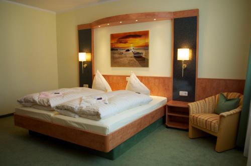 ein Schlafzimmer mit einem Bett, einem Stuhl und einem Spiegel in der Unterkunft Gasthof & Pension Zum Himmel in Rubenow