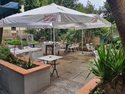 a patio with tables and chairs and an umbrella at Bella Napoli Guesthouse Trattoria Pizzeria in La Spezia