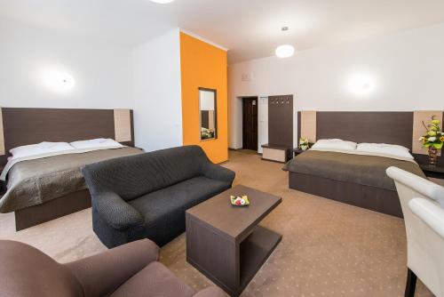 um quarto de hotel com duas camas e um sofá e uma sala de estar em Penzión RESA em Spišská Nová Ves