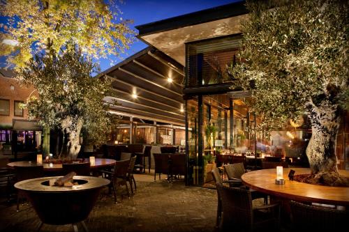 een restaurant met tafels, stoelen en bomen bij Hotel De Schout in Denekamp