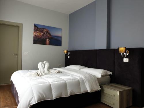 un dormitorio con una cama grande con sábanas blancas en Perandor Beach, en Durrës