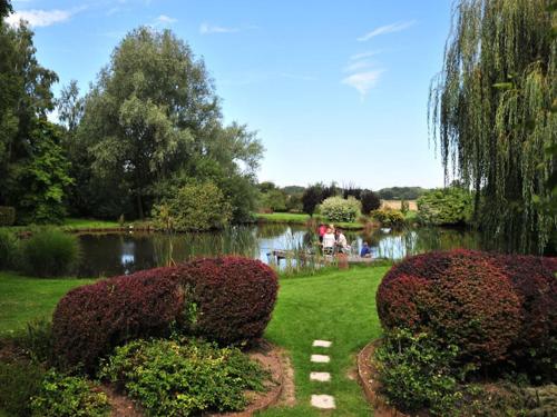 a garden with a pond and some bushes at Les Roulottes de Troussures in Troussures