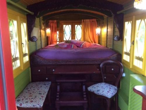 a bedroom with a bed and two chairs in a room at Les Roulottes de Troussures in Troussures