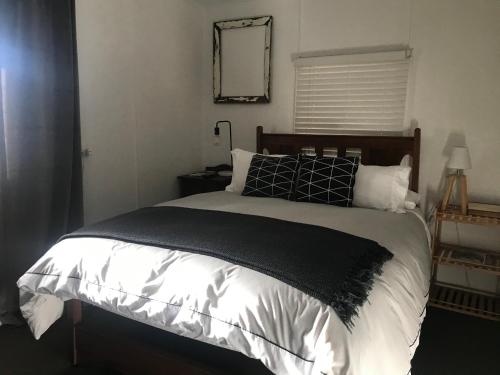 um quarto com uma cama com almofadas pretas e brancas em Fergusons Store em Heathcote