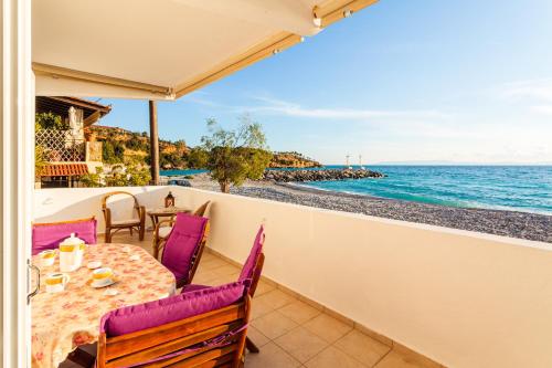 a balcony with a table and chairs and the ocean at On the Beach - Akroyali Family Home in Akrogiali