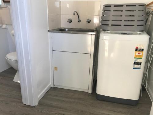 Una pequeña cocina con fregadero y refrigerador. en Fergusons Store, en Heathcote