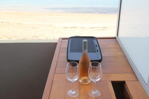 deux verres à vin et une bouteille sur une table avec la plage dans l'établissement studio pieds dans l’eau, à Ajaccio