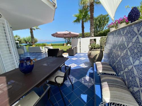 eine Terrasse mit einem Tisch, Stühlen und Palmen in der Unterkunft Casa Vacanze Ibiscus in Alcamo Marina