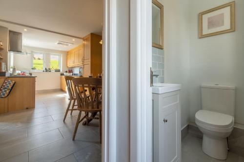 a bathroom with a toilet and a kitchen with a table at 1 Riverside Cottage in Burnsall