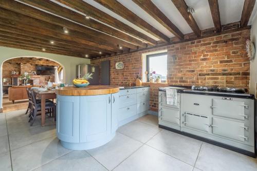 a kitchen with white cabinets and a brick wall at Five Acres in Thirsk