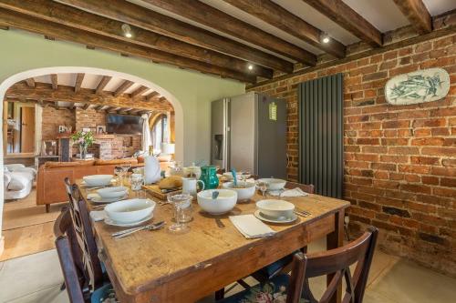a dining room with a table and a brick wall at Five Acres in Thirsk