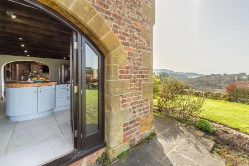 an outdoor kitchen with a view of the countryside through a brick building at Five Acres in Thirsk