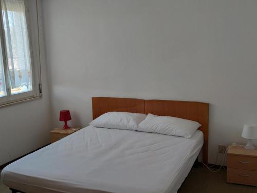 1 dormitorio con 1 cama con sábanas blancas y cabecero de madera. en Casa al mare, en Marotta