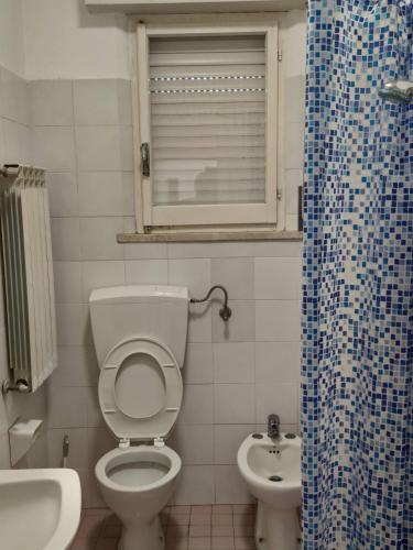 baño con aseo y lavabo y ventana en Casa al mare, en Marotta