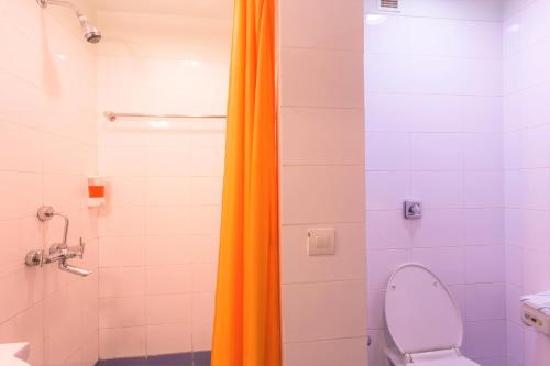 an orange shower curtain in a bathroom with a toilet at Ginger Ahmedabad Vastrapur in Ahmedabad